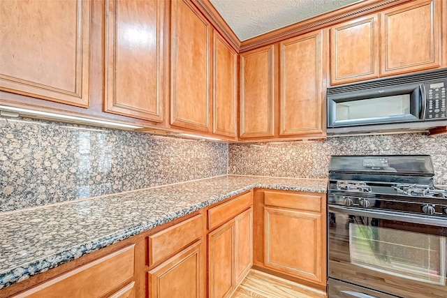 kitchen with dark stone countertops, decorative backsplash, and black appliances