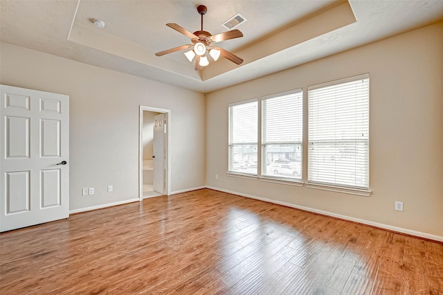 spare room featuring ceiling fan, a raised ceiling, and light wood-type flooring