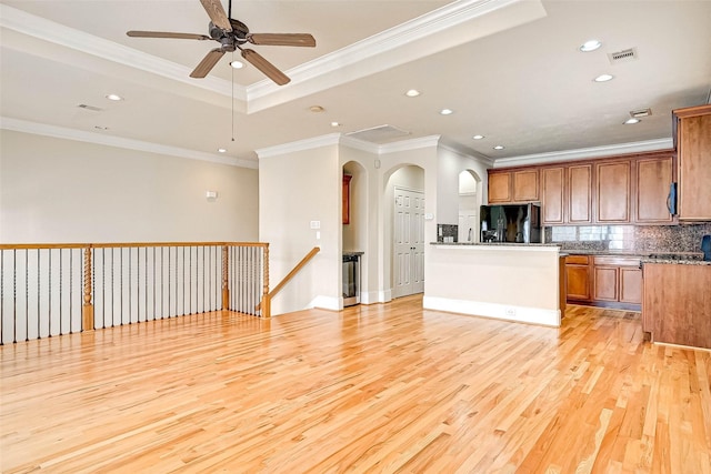 kitchen with crown molding, light hardwood / wood-style floors, decorative backsplash, black fridge with ice dispenser, and a raised ceiling