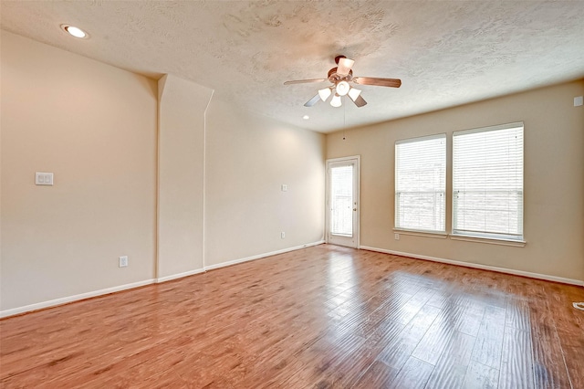 empty room with a textured ceiling, light hardwood / wood-style floors, and ceiling fan