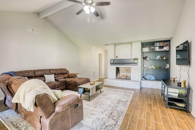 living room featuring ceiling fan, hardwood / wood-style floors, lofted ceiling with beams, a textured ceiling, and a brick fireplace