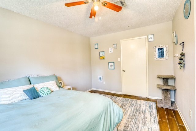 bedroom with a textured ceiling, dark wood-type flooring, and ceiling fan