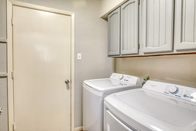 clothes washing area featuring cabinets and washer and dryer