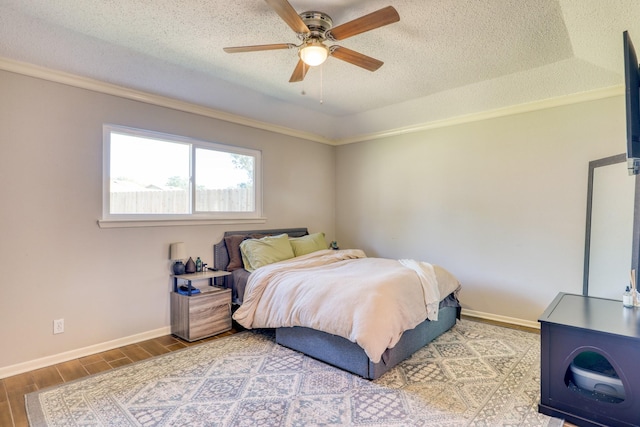 bedroom featuring ornamental molding, a textured ceiling, ceiling fan, and a tray ceiling