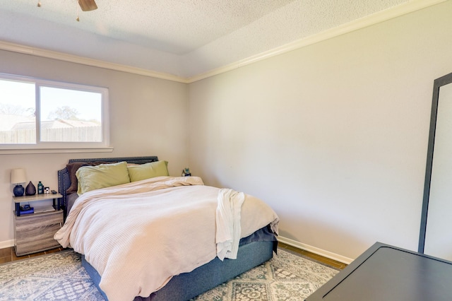 bedroom featuring ornamental molding, ceiling fan, a raised ceiling, a textured ceiling, and light hardwood / wood-style flooring