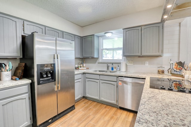 kitchen with stainless steel appliances, sink, decorative backsplash, and a textured ceiling