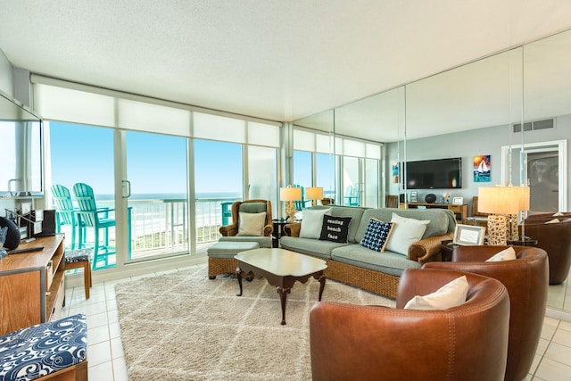 living area with expansive windows, visible vents, a textured ceiling, and light tile patterned flooring