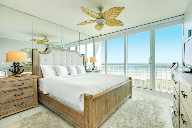 bedroom featuring expansive windows, light tile patterned floors, multiple windows, and a ceiling fan