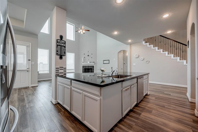 kitchen with stainless steel appliances, sink, white cabinets, and a kitchen island with sink