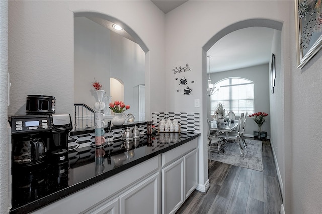 kitchen featuring white cabinetry, dark wood-type flooring, dark stone counters, and an inviting chandelier