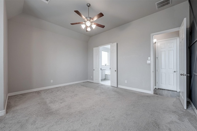 unfurnished bedroom featuring vaulted ceiling, light colored carpet, ceiling fan, and ensuite bath