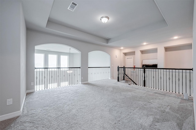 carpeted spare room with a raised ceiling