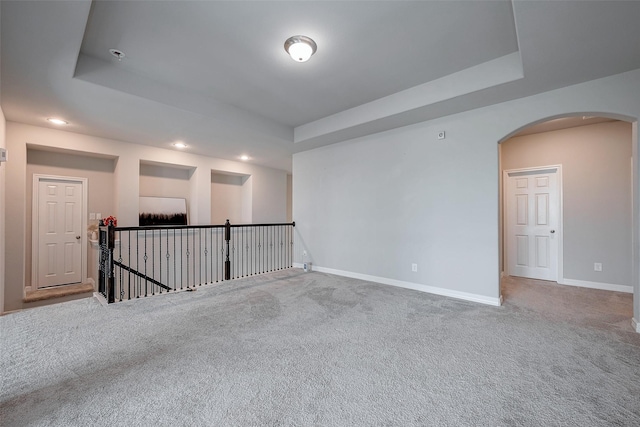 empty room with a raised ceiling and carpet