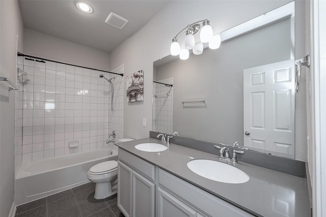 full bathroom featuring vanity, tiled shower / bath combo, tile patterned floors, and toilet