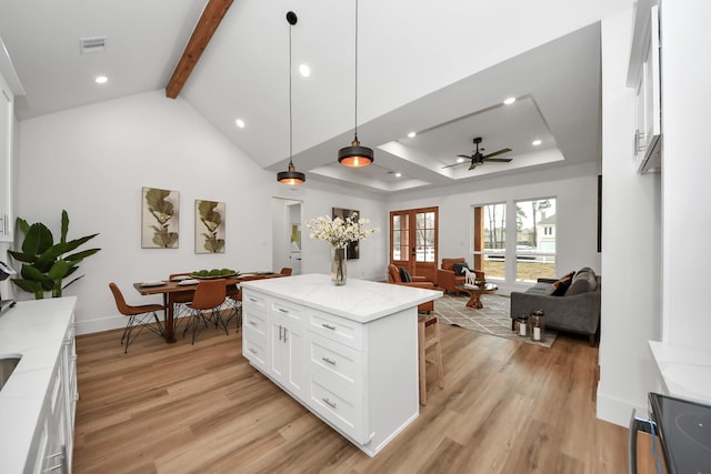 kitchen with white cabinetry, hanging light fixtures, light stone countertops, and a center island