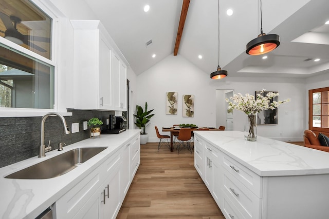 kitchen featuring pendant lighting, sink, white cabinets, decorative backsplash, and light hardwood / wood-style flooring