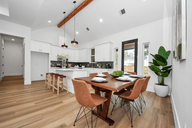 dining area with beam ceiling, light hardwood / wood-style floors, and high vaulted ceiling