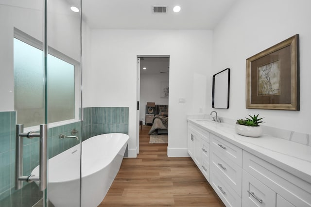 bathroom with hardwood / wood-style flooring, vanity, a bath, and a wealth of natural light