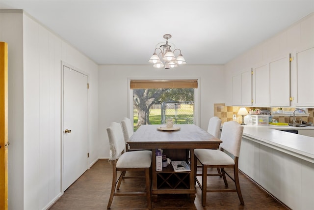 dining area with dark wood-type flooring, sink, and a notable chandelier