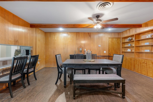 dining space featuring hardwood / wood-style floors, beamed ceiling, ceiling fan, and wood walls