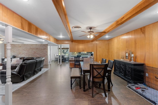 dining room featuring dark hardwood / wood-style floors, ceiling fan, wooden walls, and beam ceiling