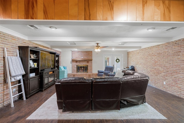 living room with beamed ceiling, dark hardwood / wood-style flooring, brick wall, and a fireplace