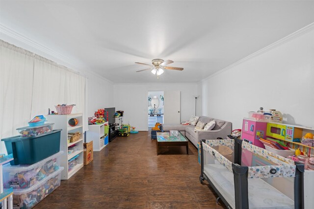 playroom featuring crown molding, dark wood-type flooring, and ceiling fan