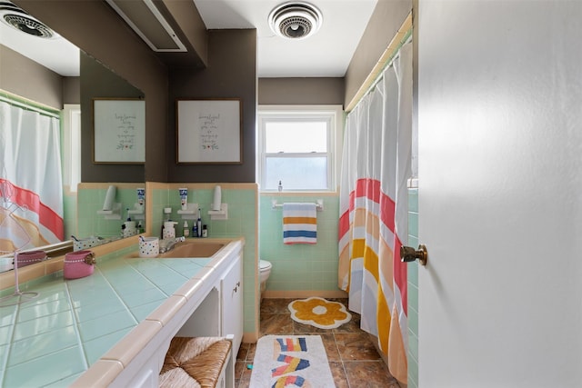 bathroom with vanity, toilet, and tile walls