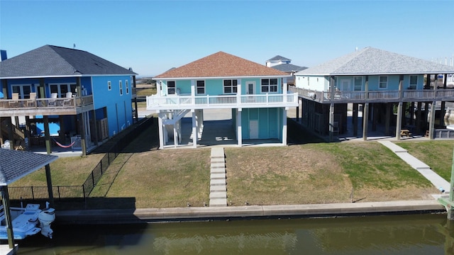 rear view of house with a water view and a lawn