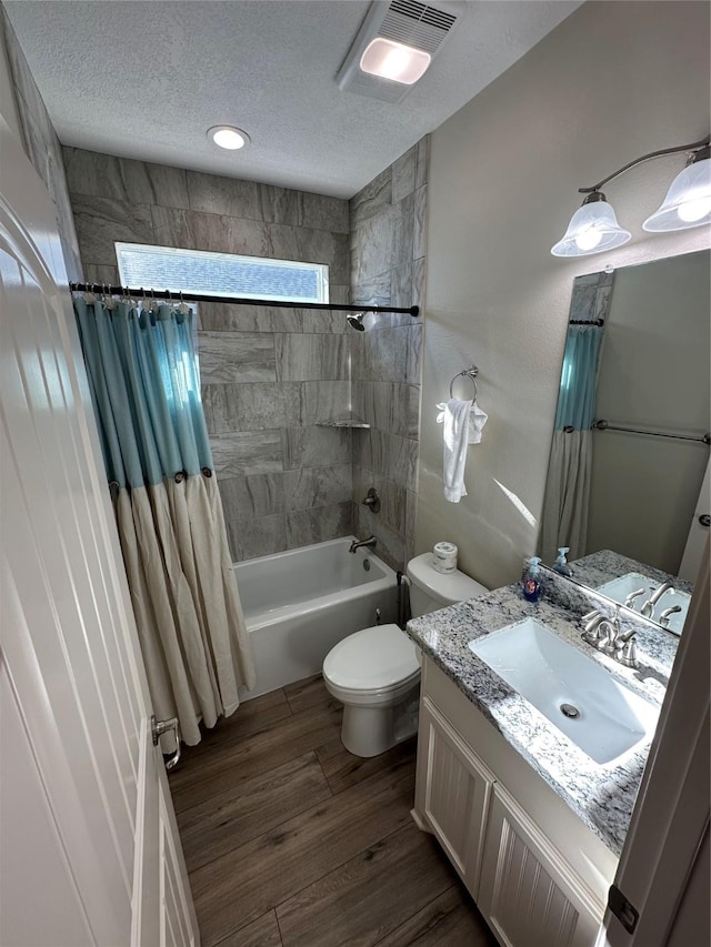 full bathroom featuring shower / tub combo, hardwood / wood-style floors, vanity, a textured ceiling, and toilet