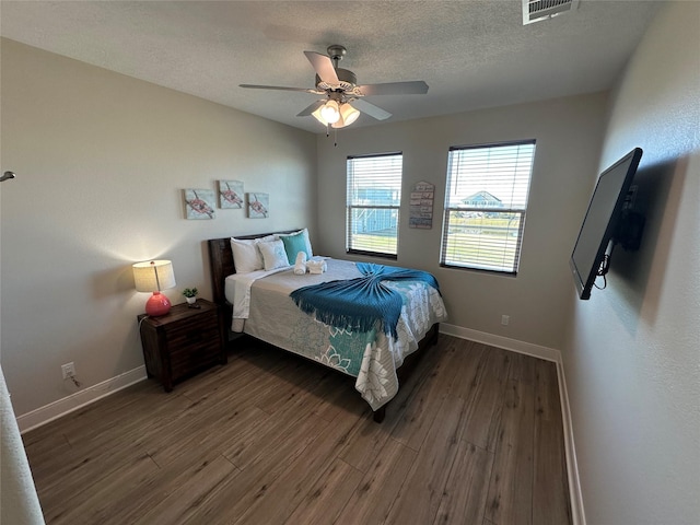 bedroom with ceiling fan, dark hardwood / wood-style flooring, and a textured ceiling