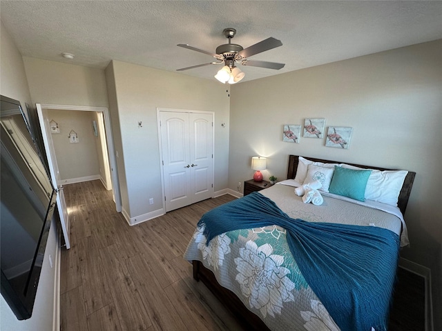 bedroom with wood-type flooring, fridge, ceiling fan, a textured ceiling, and a closet