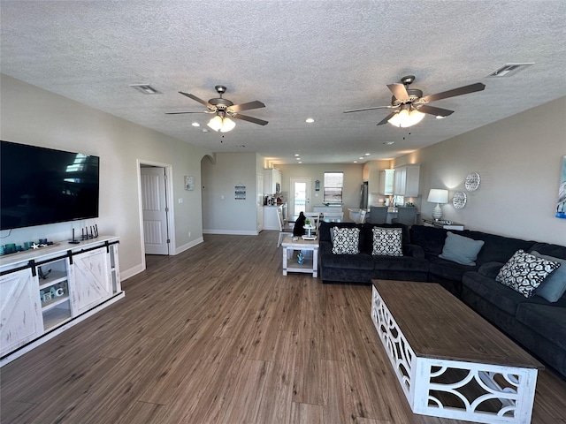 unfurnished living room with a textured ceiling, dark wood-type flooring, and ceiling fan