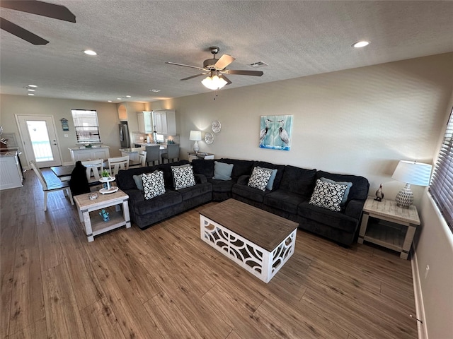 living room with hardwood / wood-style floors, a textured ceiling, and ceiling fan