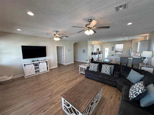 living room with ceiling fan, hardwood / wood-style flooring, and a textured ceiling