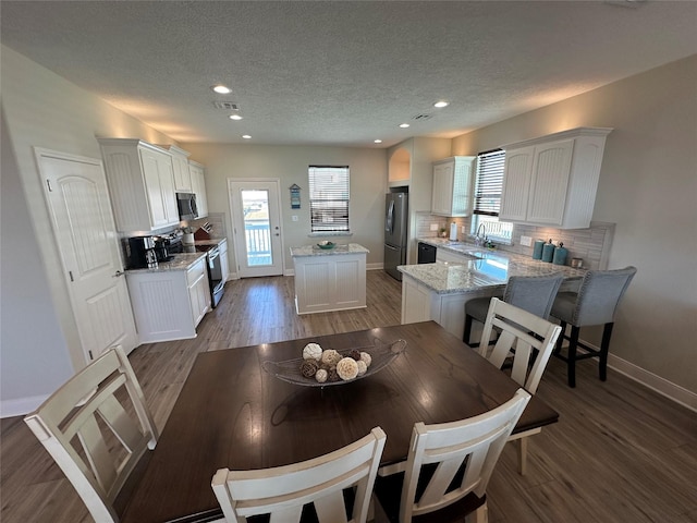 dining space with wood-type flooring, sink, and a textured ceiling