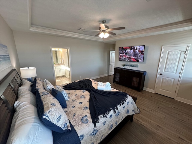 bedroom with dark wood-type flooring, ensuite bath, ornamental molding, and a tray ceiling