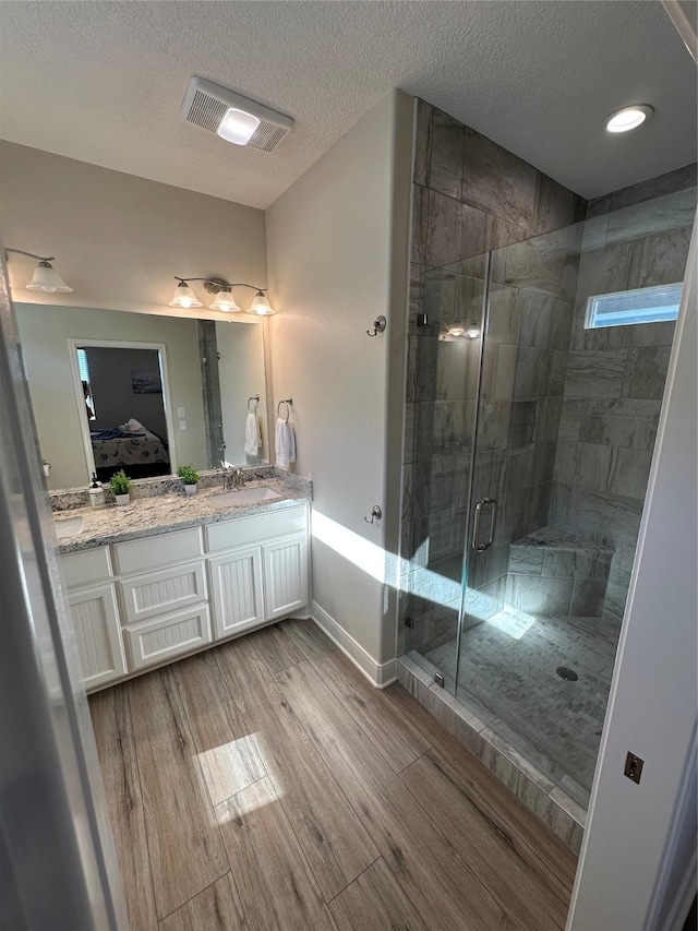 bathroom with hardwood / wood-style flooring, vanity, a textured ceiling, and walk in shower