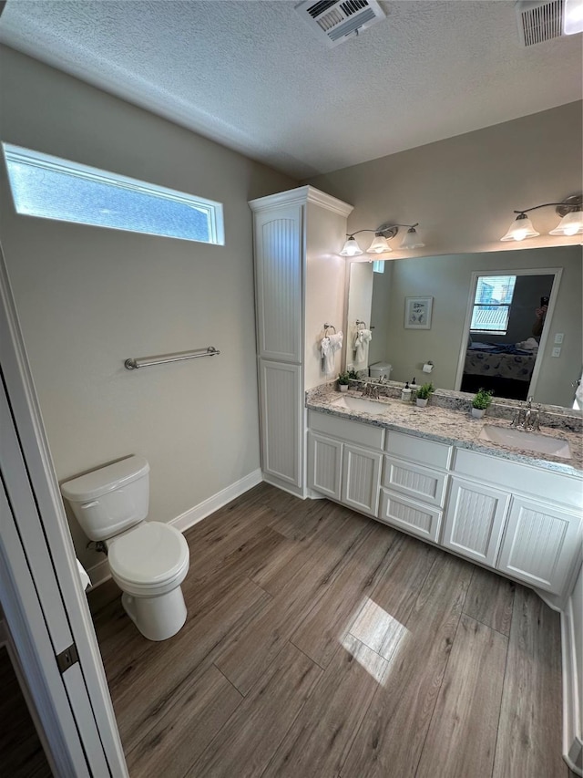 bathroom with hardwood / wood-style flooring, vanity, a textured ceiling, and toilet