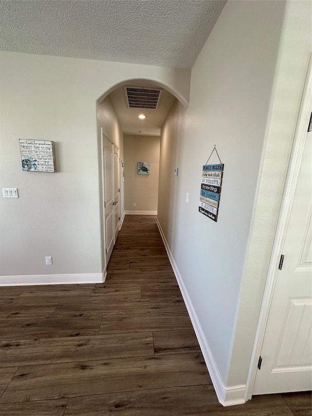 corridor with dark hardwood / wood-style flooring and a textured ceiling