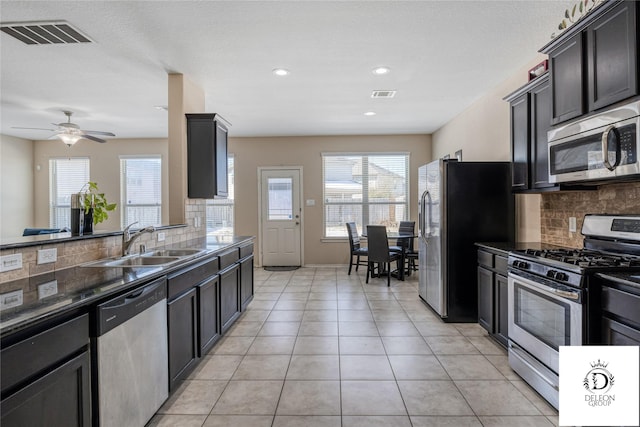 kitchen with tasteful backsplash, appliances with stainless steel finishes, light tile patterned flooring, and sink