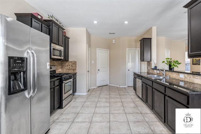 kitchen with light tile patterned flooring, sink, dark stone counters, decorative backsplash, and stainless steel appliances