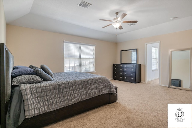 bedroom with a raised ceiling, vaulted ceiling, and light colored carpet