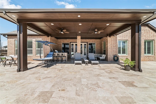 view of patio / terrace featuring a bar, outdoor lounge area, and ceiling fan