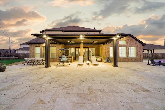 back house at dusk with a patio area and ceiling fan