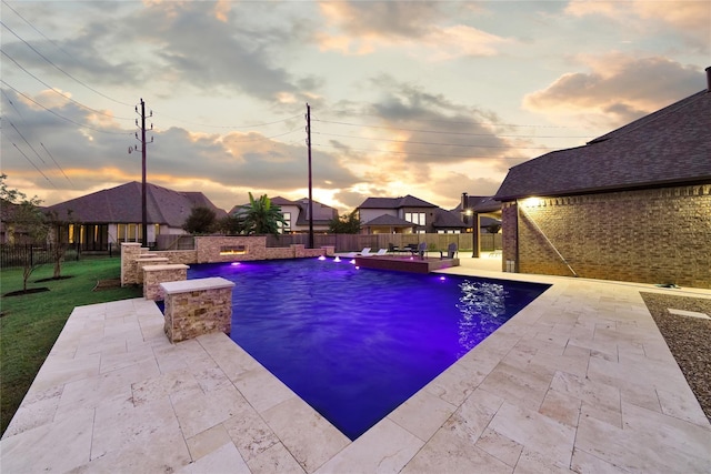 pool at dusk with a patio and pool water feature