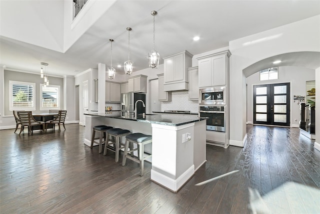 kitchen featuring pendant lighting, gray cabinets, a breakfast bar area, backsplash, and stainless steel appliances