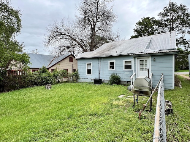 back of property featuring a yard and central AC