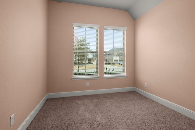 carpeted spare room with vaulted ceiling