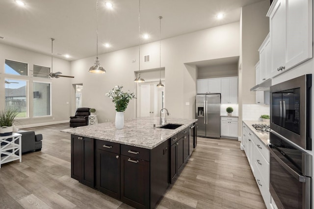 kitchen with sink, white cabinetry, appliances with stainless steel finishes, pendant lighting, and decorative backsplash